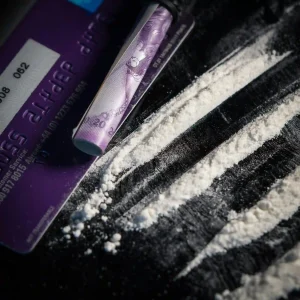 Imagem mostrando um cartão de crédito e uma substância branca em pó, evidenciando o uso de drogas e suas implicações.